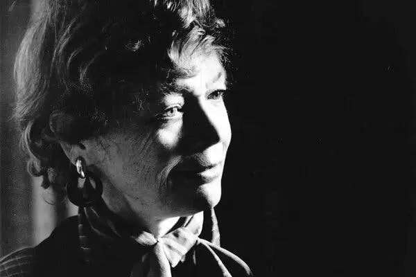 عکسی سیاه‑سفید، ملانکس از چهرهٔ یک زن به‌صورت نزدیک. موهای او کوتاه و موج‌دار، گوشوارهٔ حلقه‌ای و یک روسری ابریشمی دور گردن گره‌خورده دارد. او به‌سمت راست قاب نگاه می‌کند و نیمه‌لبخند دارد. 