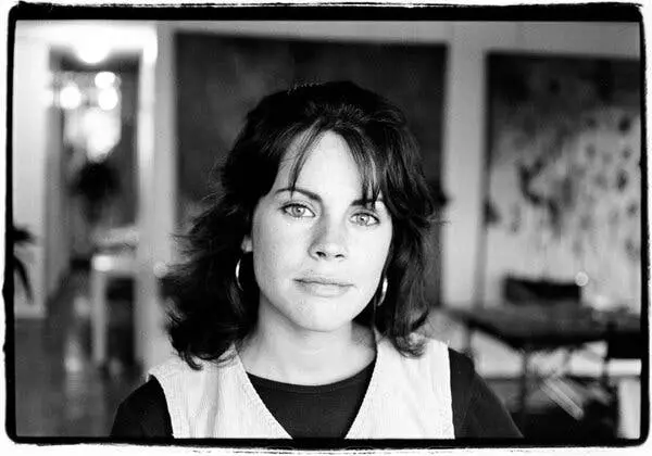 عکسی سیاهسفید از ژان کرواک که گوشوارههای حلقی، جلیقهای رنگ روشن و پیراهنی تیره به تن دارد.